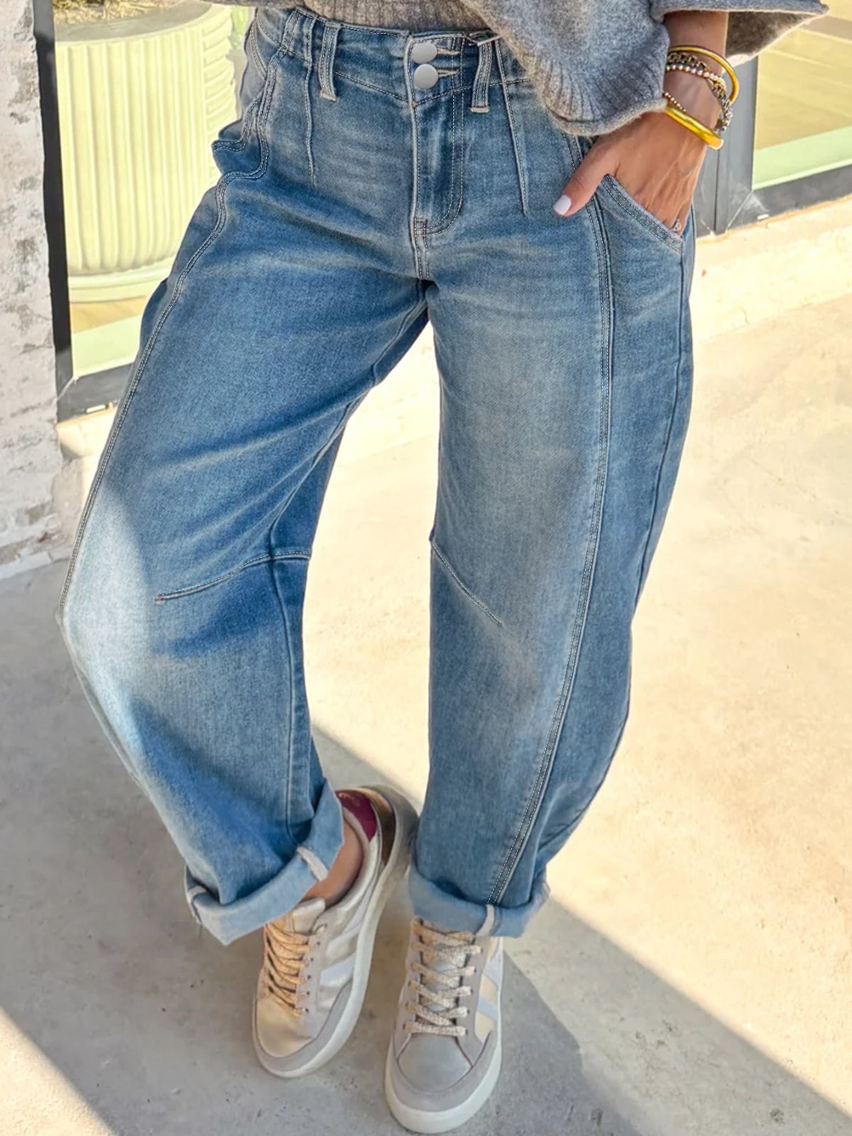 Person wearing blue jeans and white sneakers on a light background