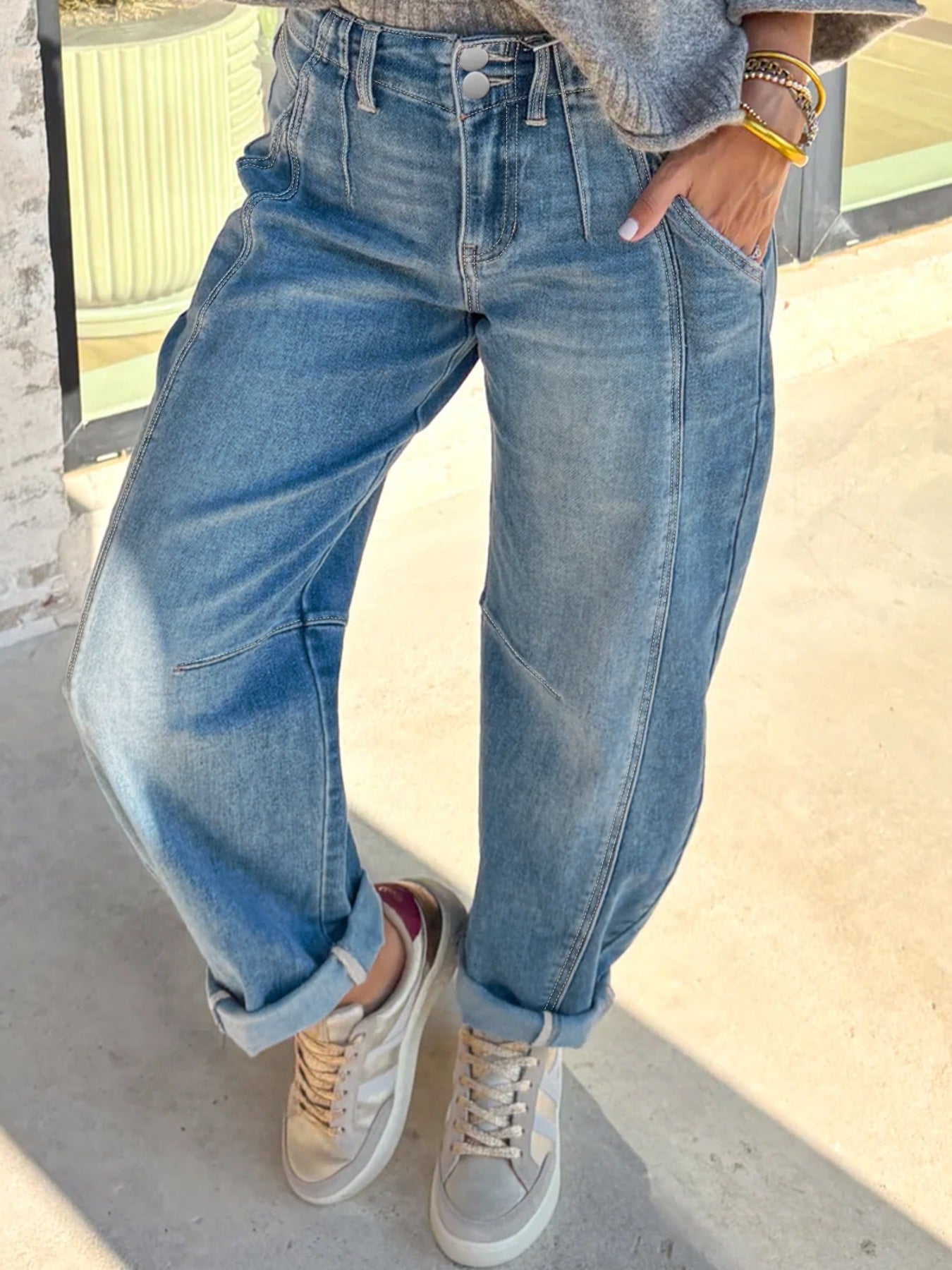 Person wearing blue jeans and white sneakers on a light background