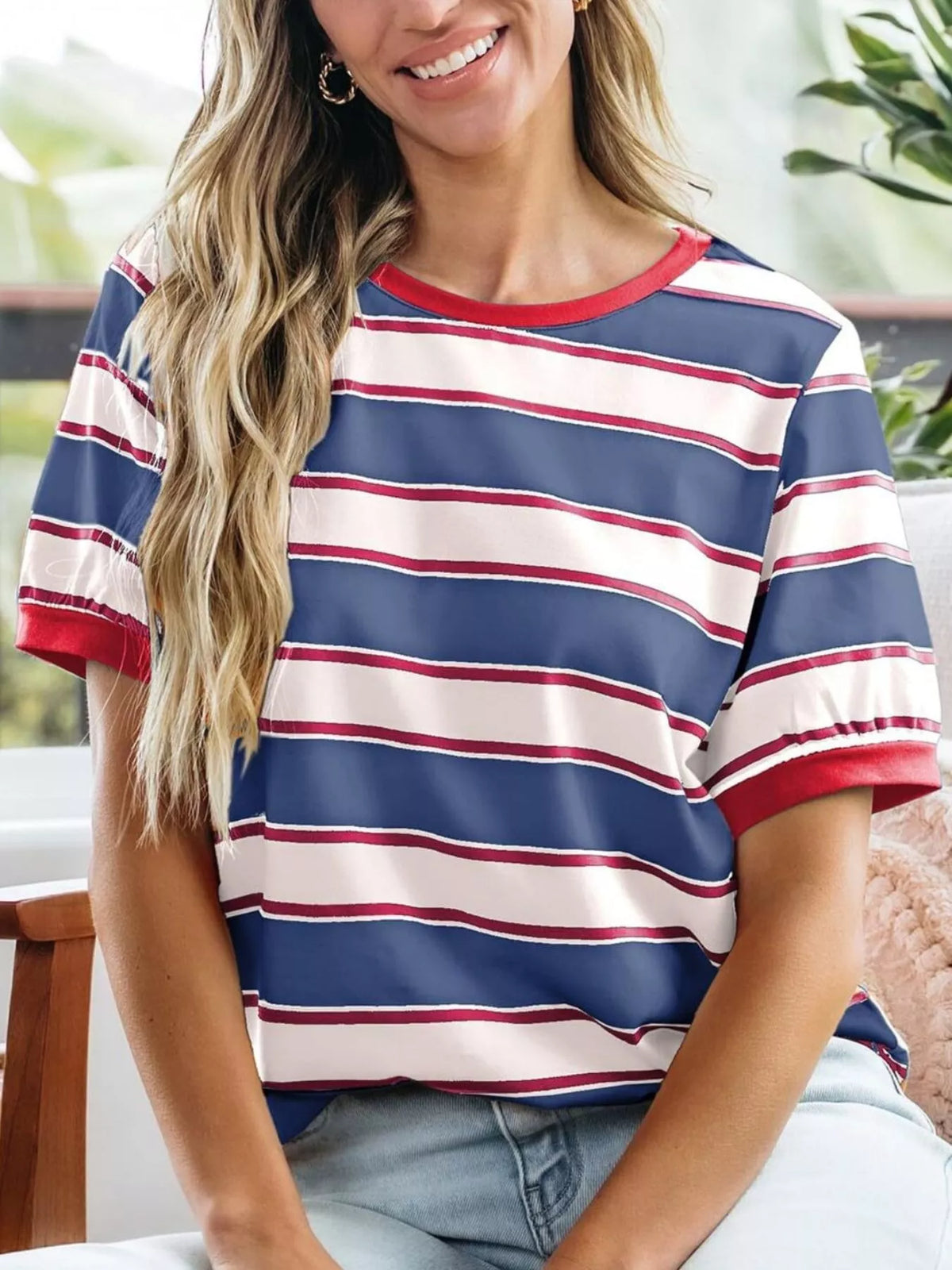 Woman wearing a red, white, and blue striped shirt sitting outdoors.