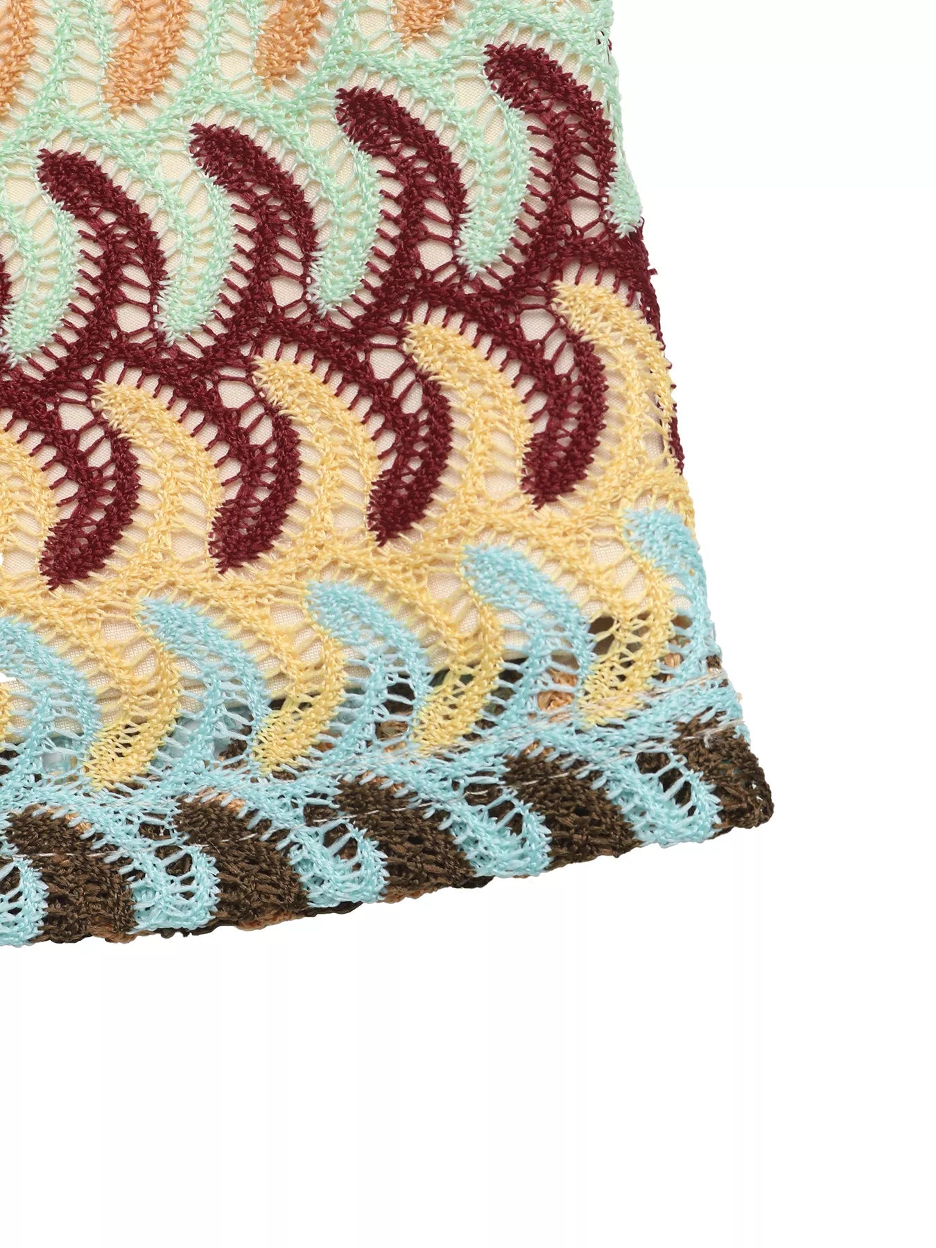 Close-up of a crocheted fabric with wavy pattern in red, yellow, and blue on a white background