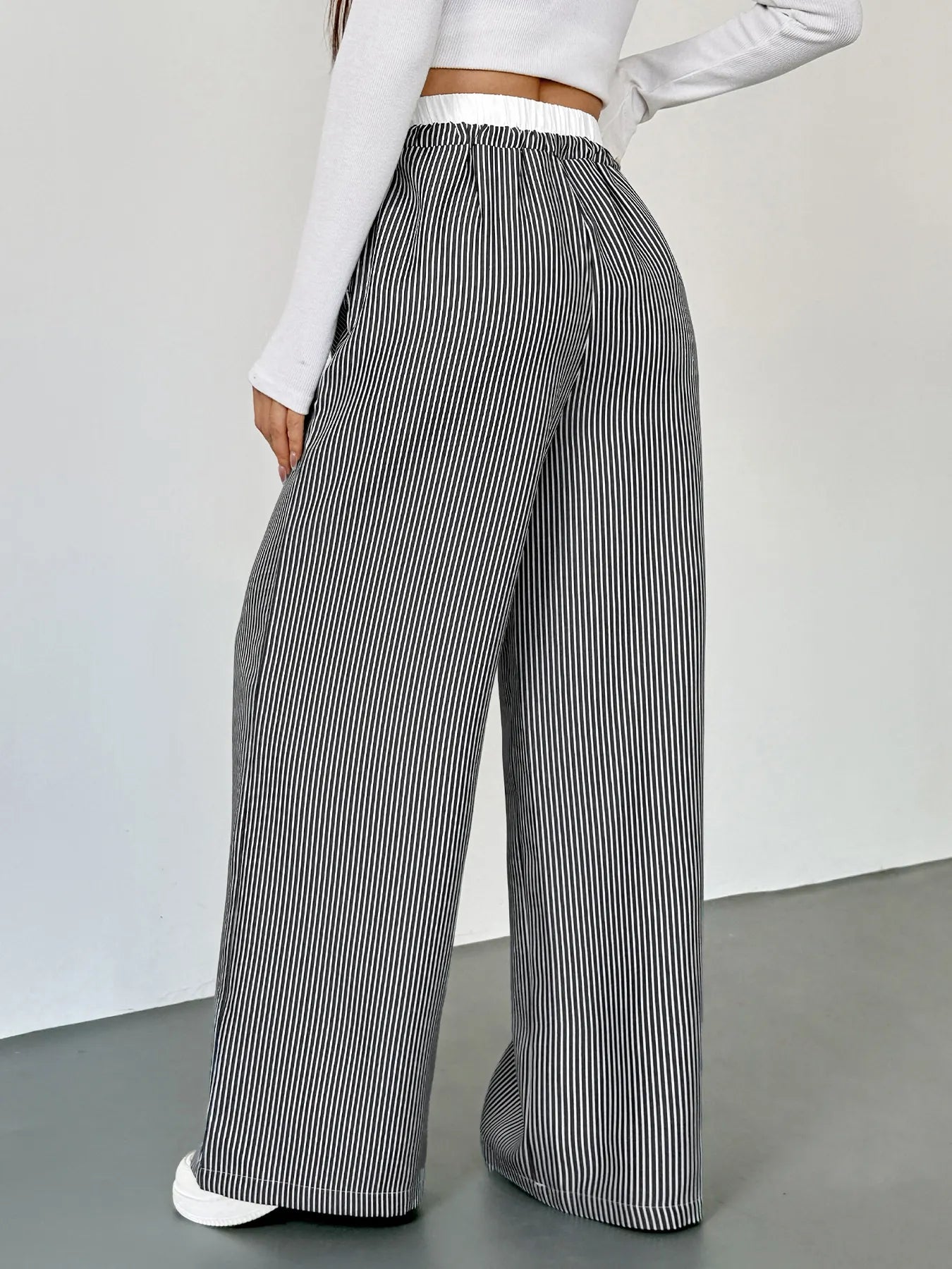 Person wearing high-waisted black and white striped pants on a plain background