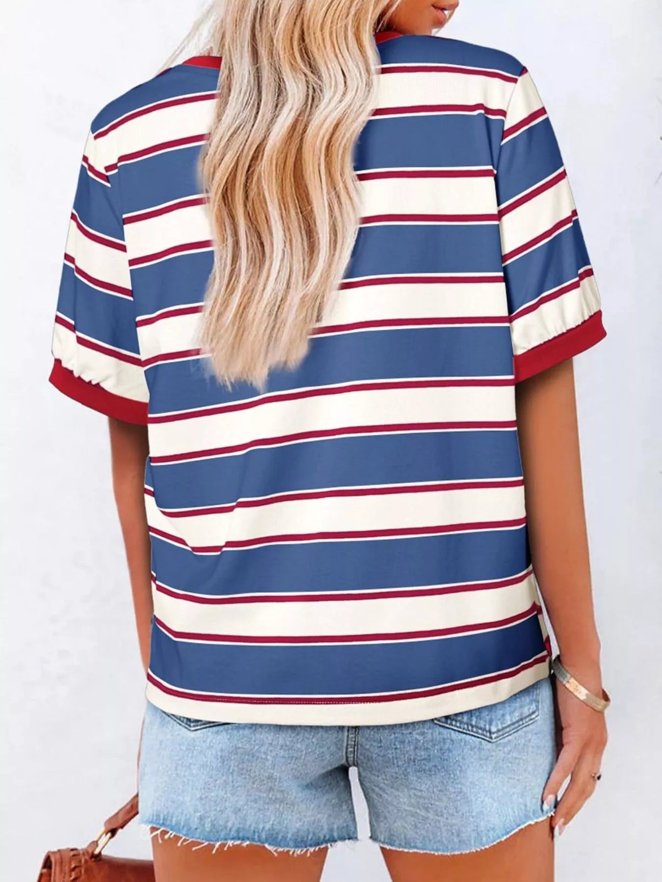Person wearing a blue, white, and red striped shirt with denim shorts on a white background