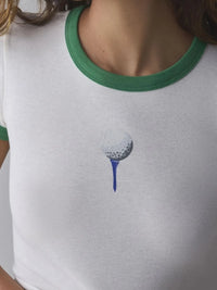 White t-shirt with green trim featuring a golf ball on a tee design.