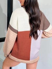 Person wearing a color-blocked sweater with beige, brown, and red sections.