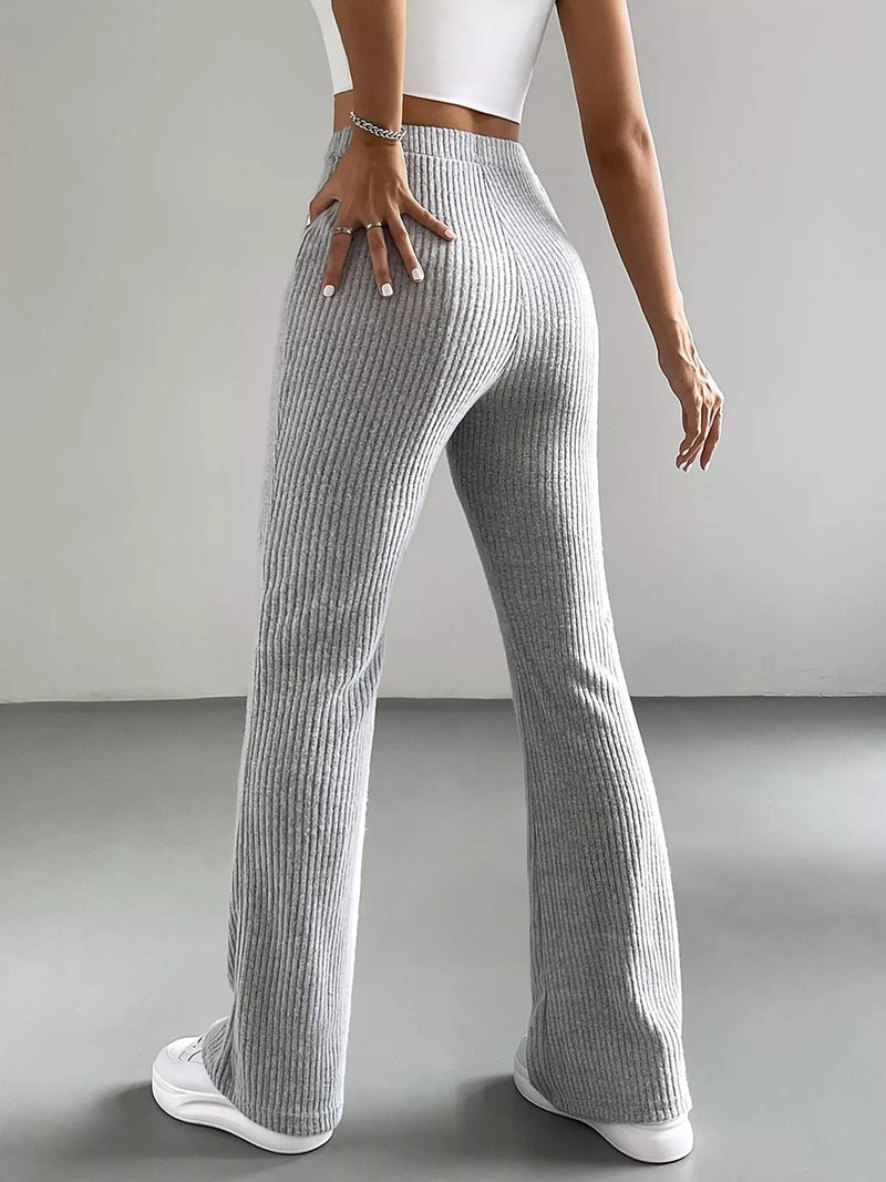 Person wearing gray ribbed pants and white sneakers on a plain background