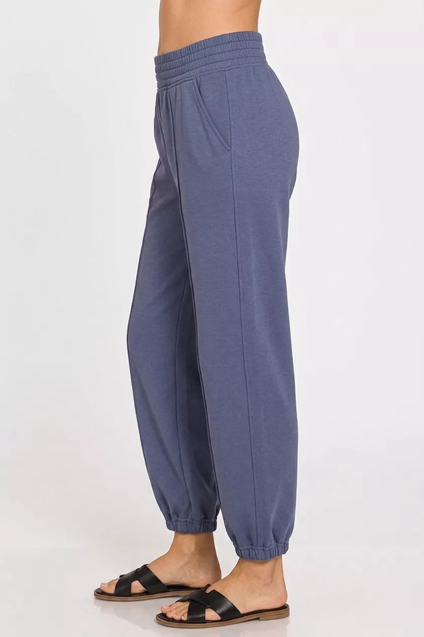 Blue jogger pants worn by a person on a white background
