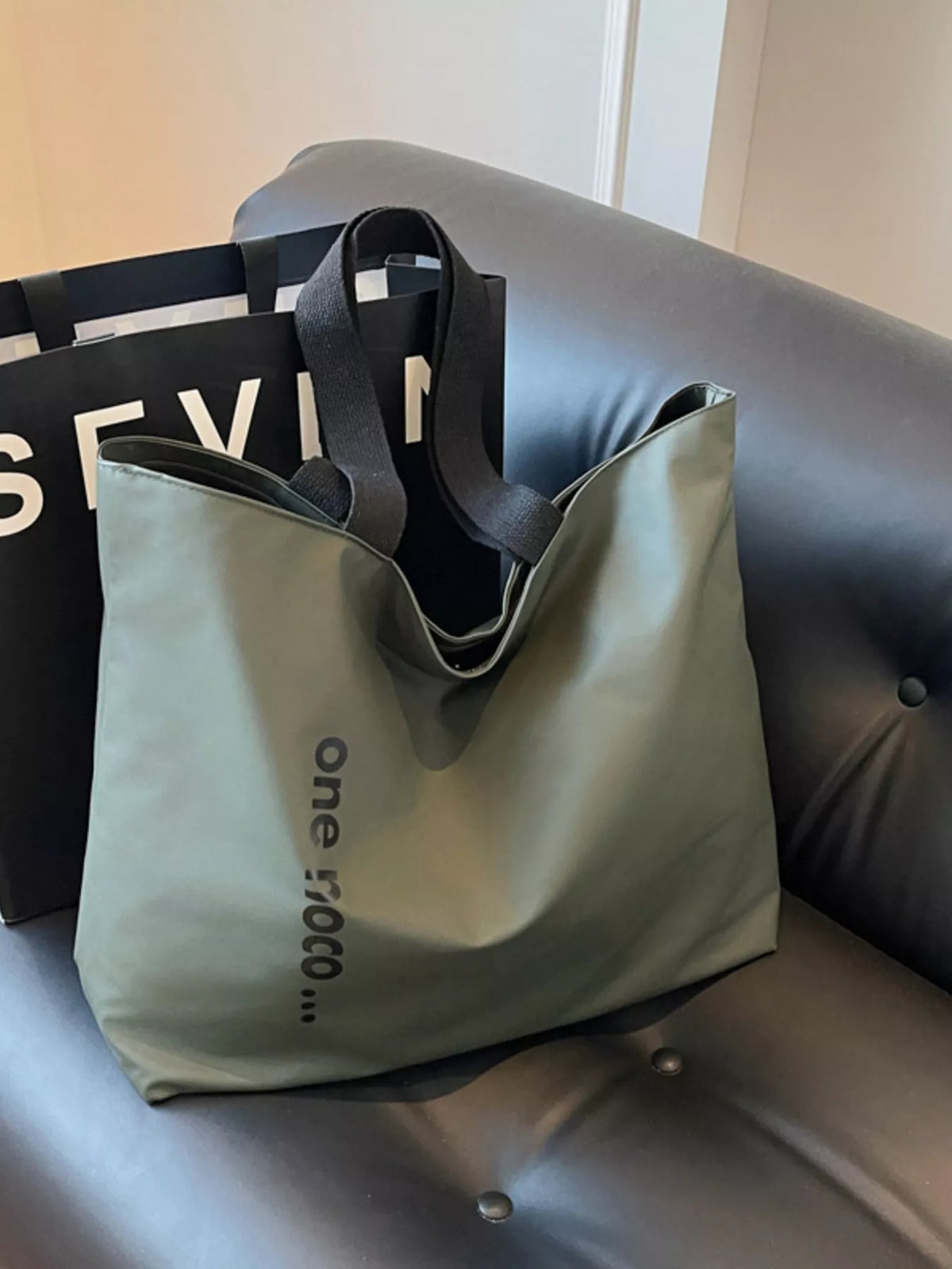 Two tote bags, one black and one beige, on a gray couch.