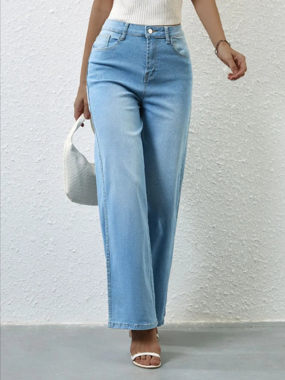 Person wearing light blue jeans against a plain background