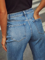 Close-up of blue jeans worn by a person with a neutral background