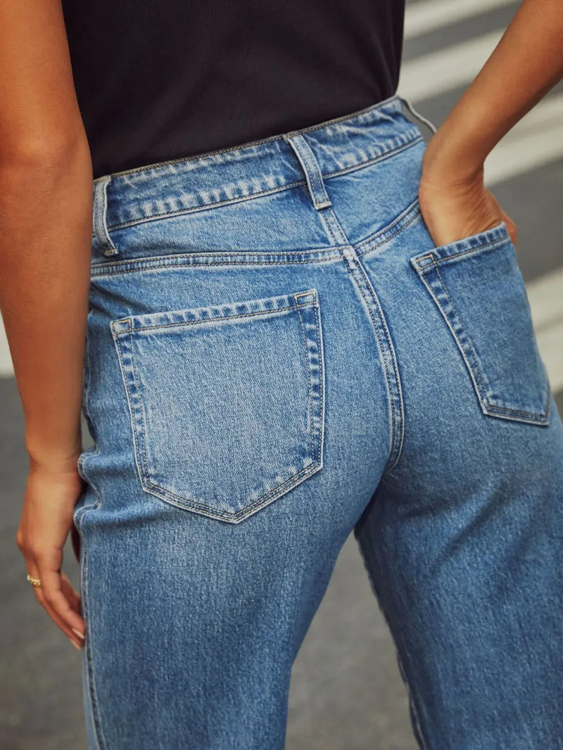 Close-up of blue jeans worn by a person with a neutral background