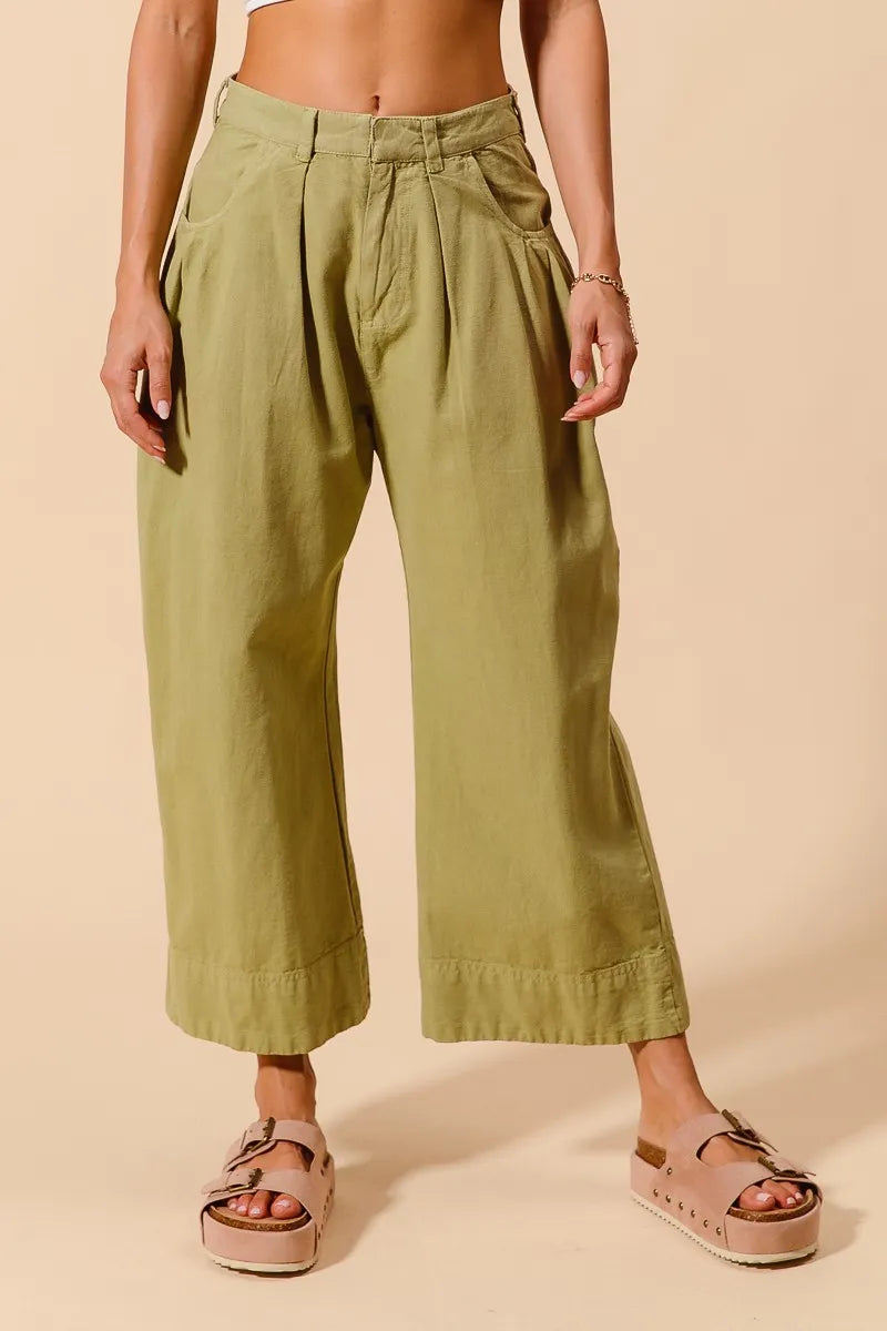 Person wearing green wide-leg pants on a beige background