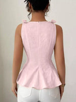 Person wearing a pink peplum top with white pants on a plain background