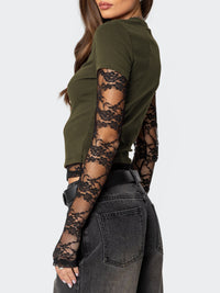 Green long-sleeve top with lace sleeves worn by a person on a white background