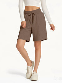 Person wearing brown shorts with a drawstring on a white background