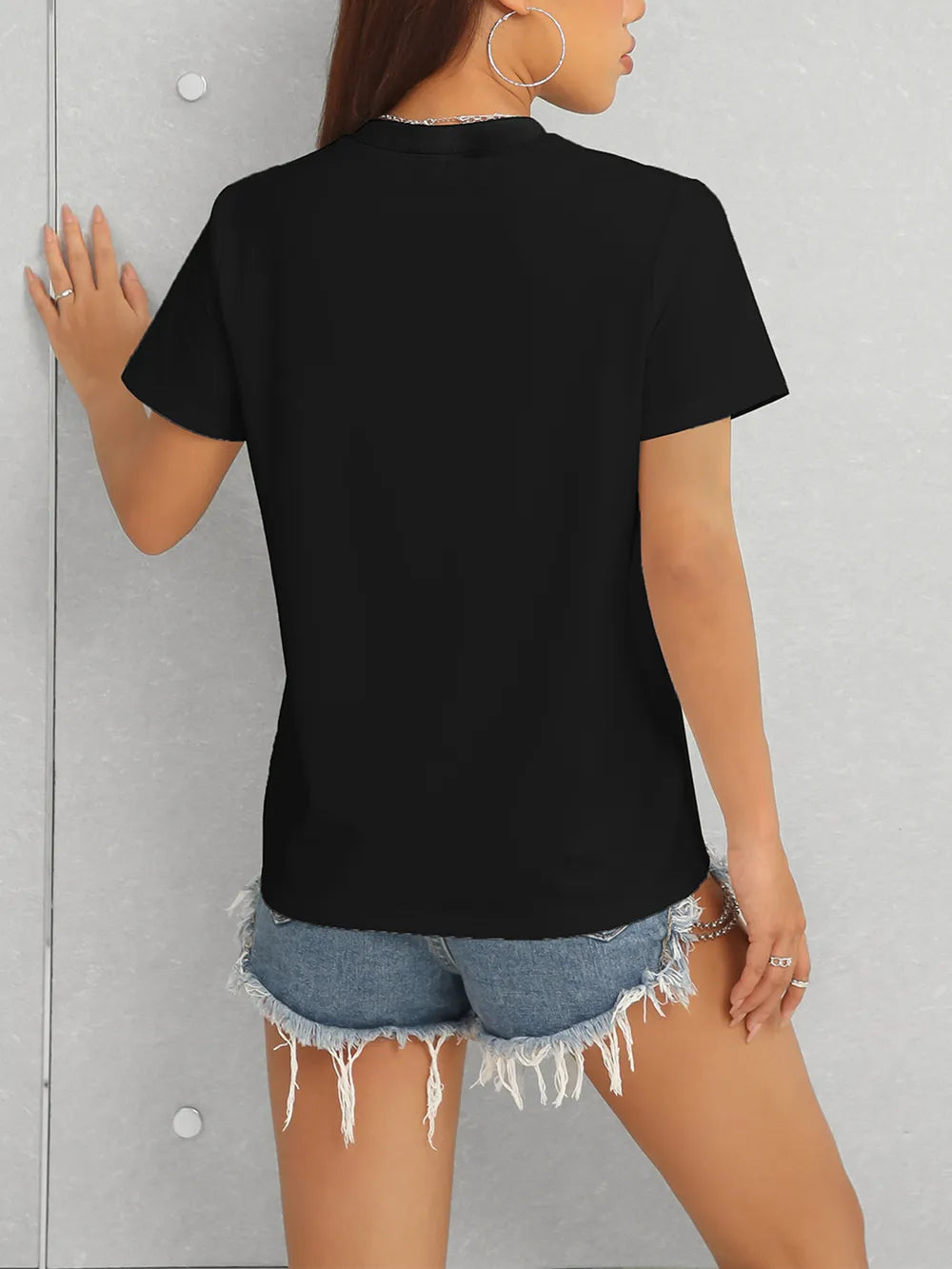 Person wearing a black t-shirt and denim shorts against a gray background
