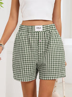 Green and white checkered shorts worn by a person on a white background