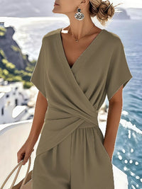 Woman wearing a green jumpsuit with a scenic background of water and buildings.