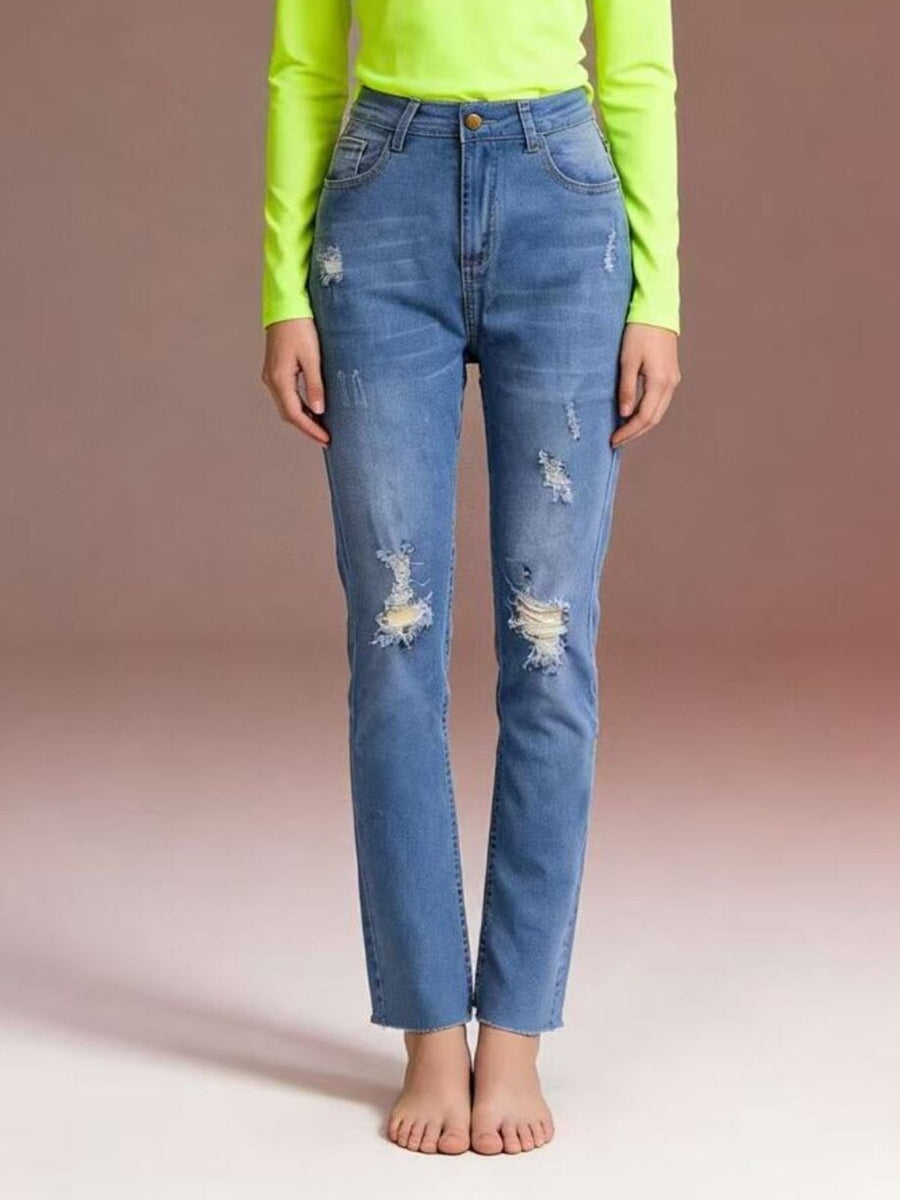 Person wearing blue distressed jeans and a bright green top on a beige background