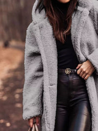 Person wearing a gray fluffy coat with a blurred outdoor background