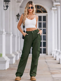 Woman wearing a white crop top and green cargo pants standing on a porch.
