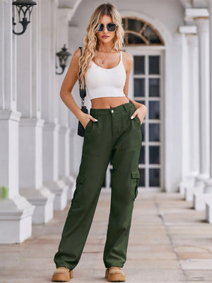 Woman wearing a white crop top and green cargo pants standing on a porch.
