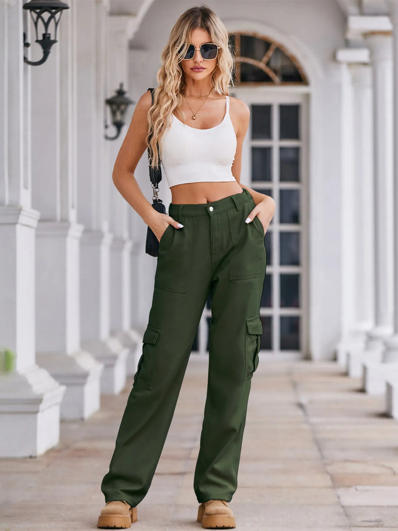 Woman wearing a white crop top and green cargo pants standing on a porch.