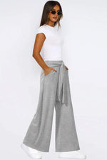 Woman wearing a white t-shirt and gray wide-leg pants on a white background