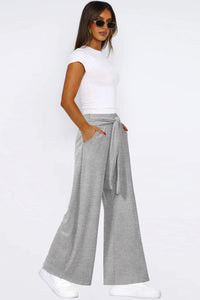 Woman wearing a white t-shirt and gray wide-leg pants on a white background
