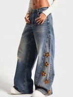 Blue jeans with floral embellishments on a white background