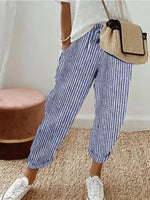 Person wearing blue and white striped pants with a beige bag in a casual setting.