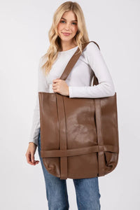 Woman holding a large brown bag against a white background