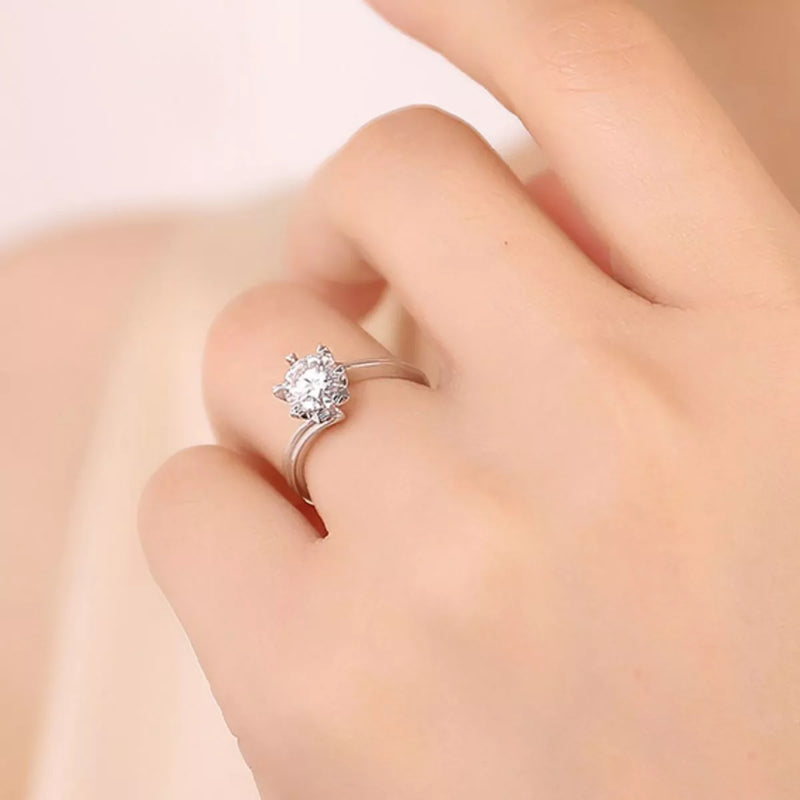 Silver ring with a diamond on a hand against a neutral background