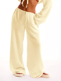 Light yellow lounge pants worn by a person on a white background