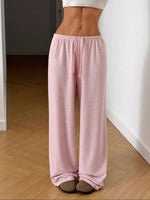 Person wearing pink pajama pants standing on a wooden floor.