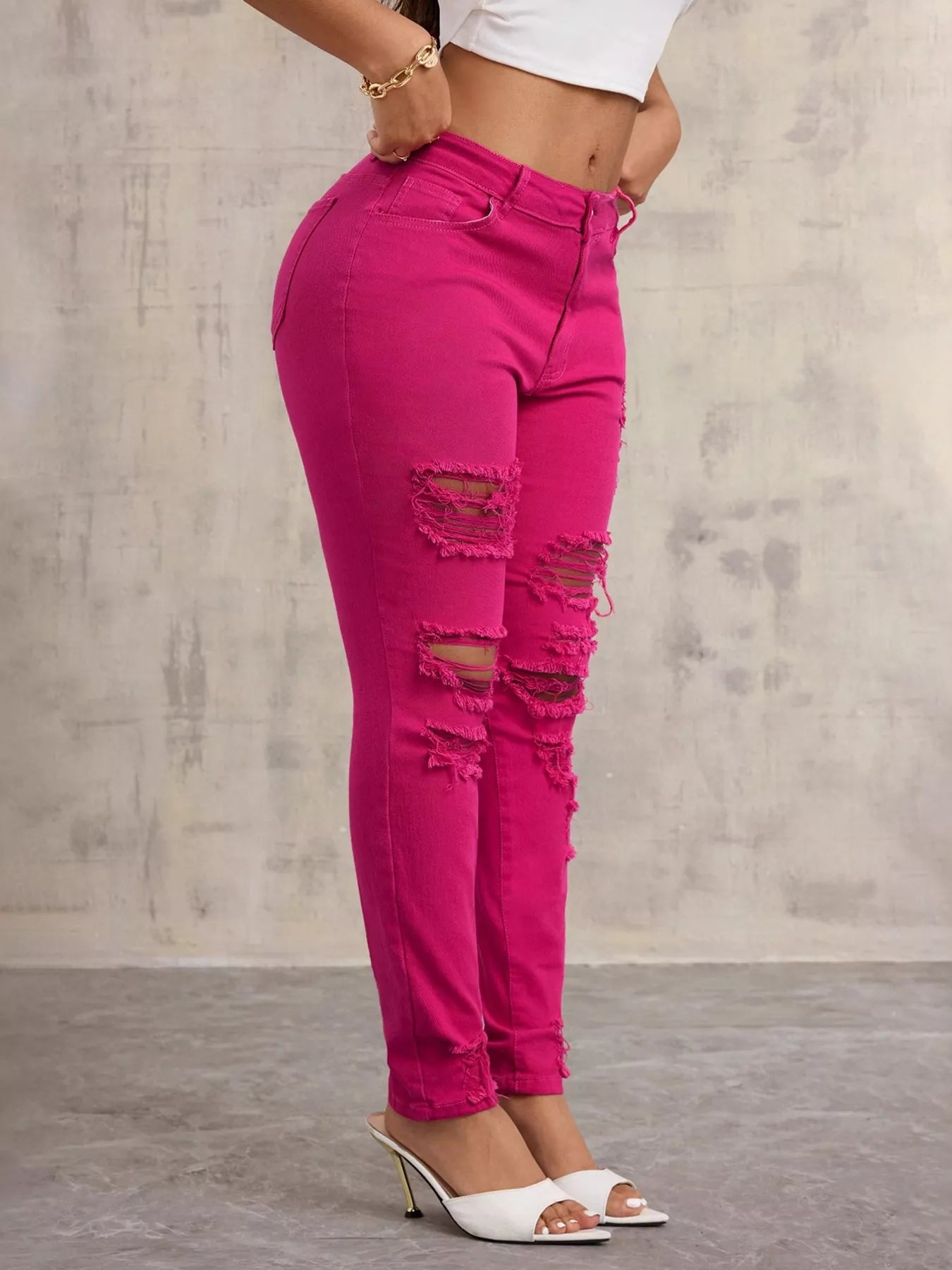 Person wearing bright pink ripped jeans against a gray background