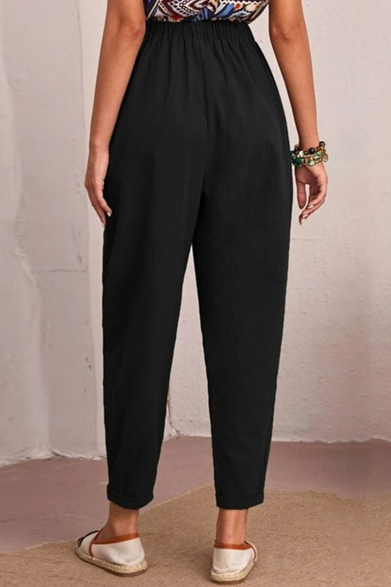 Person wearing black pants with a plain background