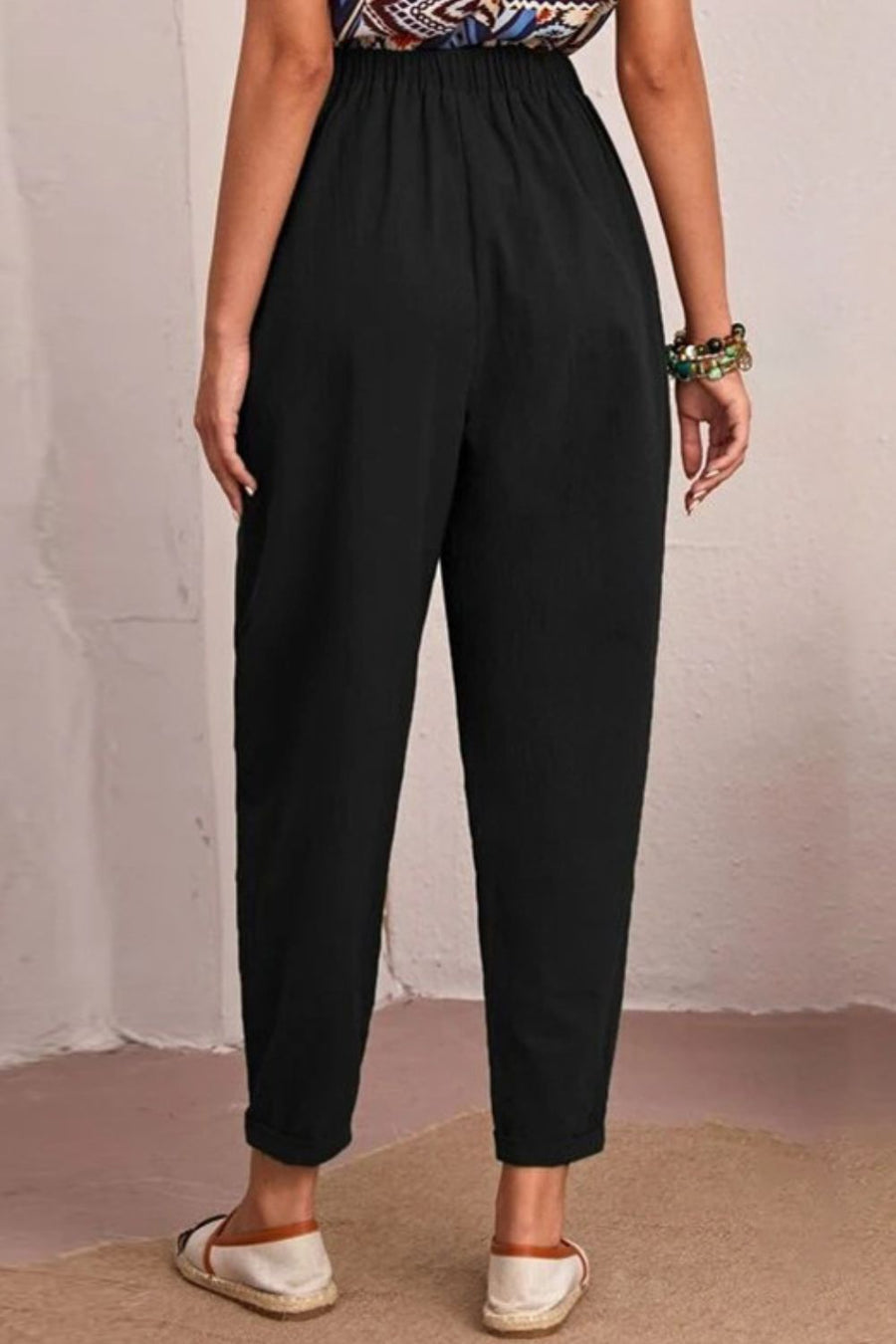 Person wearing black pants with a plain background