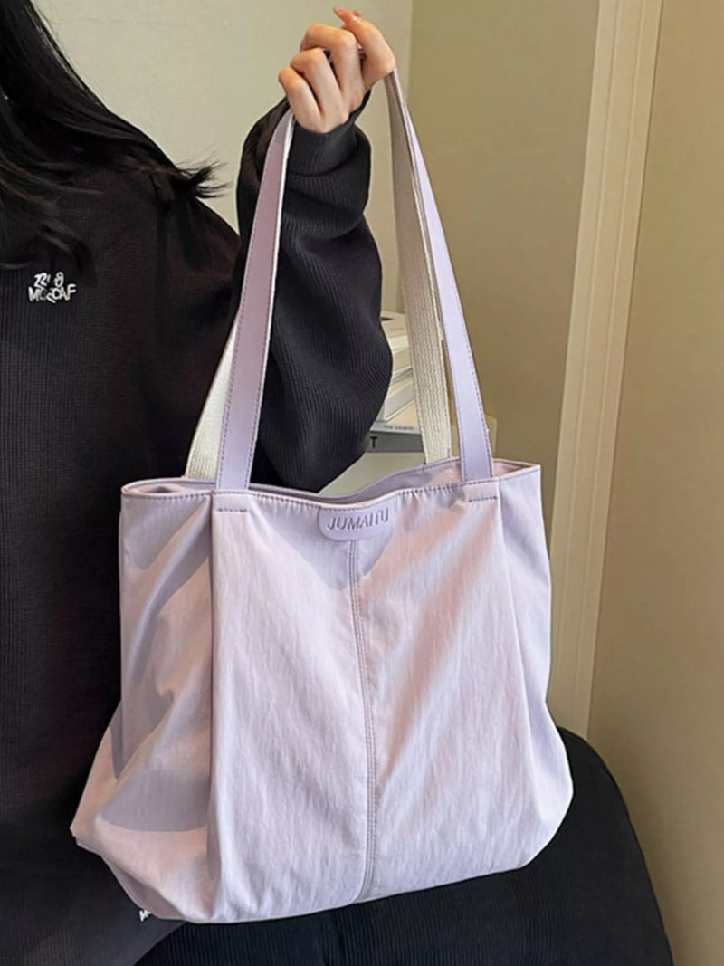 Person holding a light purple tote bag with 'JUUN.J' branding.
