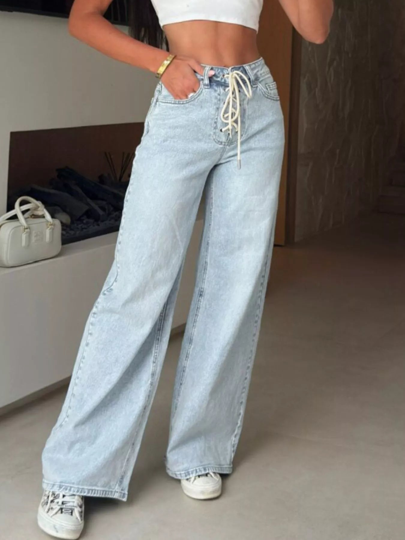 Person wearing light blue jeans with a white top in an indoor setting