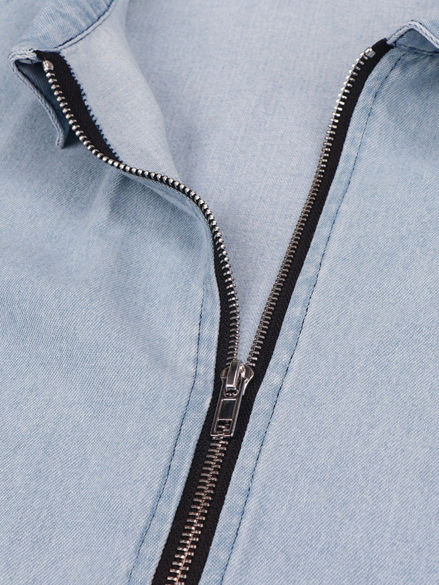 Close-up of a light blue denim jacket with a black zipper.