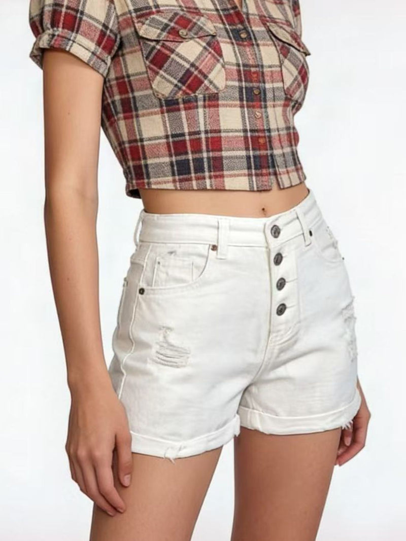 Person wearing a plaid shirt and white shorts on a plain background