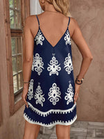 Woman wearing a navy blue dress with white patterns in an indoor setting.