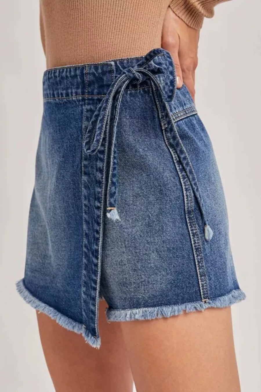 Denim skirt with tie waist on a plain background