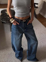 Person wearing blue jeans and a gray top in a room with a rug and furniture.
