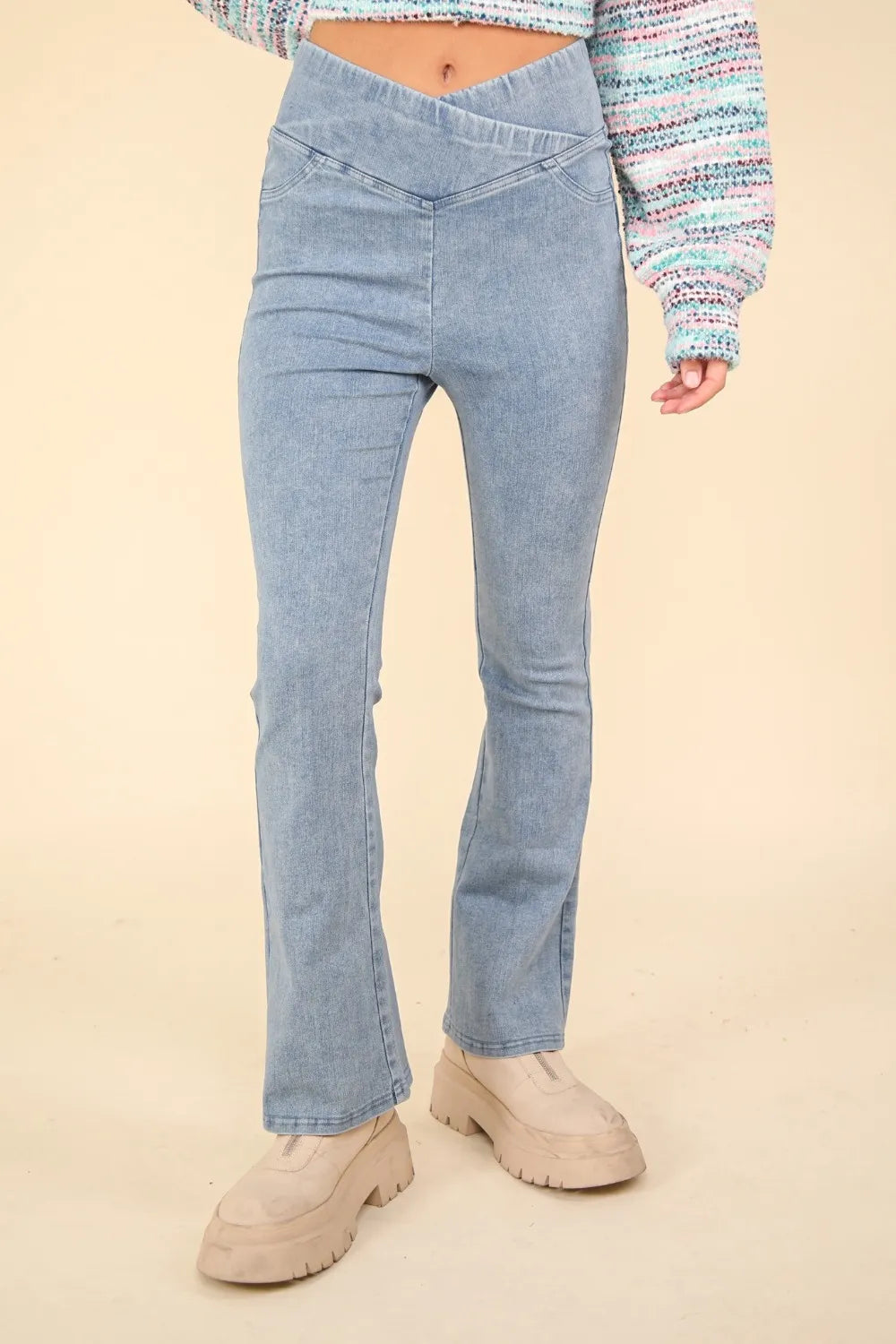 Light blue jeans worn by a person on a beige background