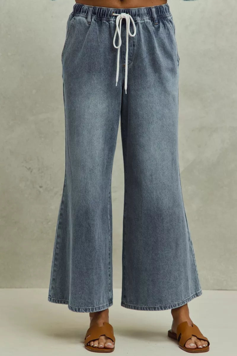 Blue denim wide-leg pants with a drawstring waist on a neutral background