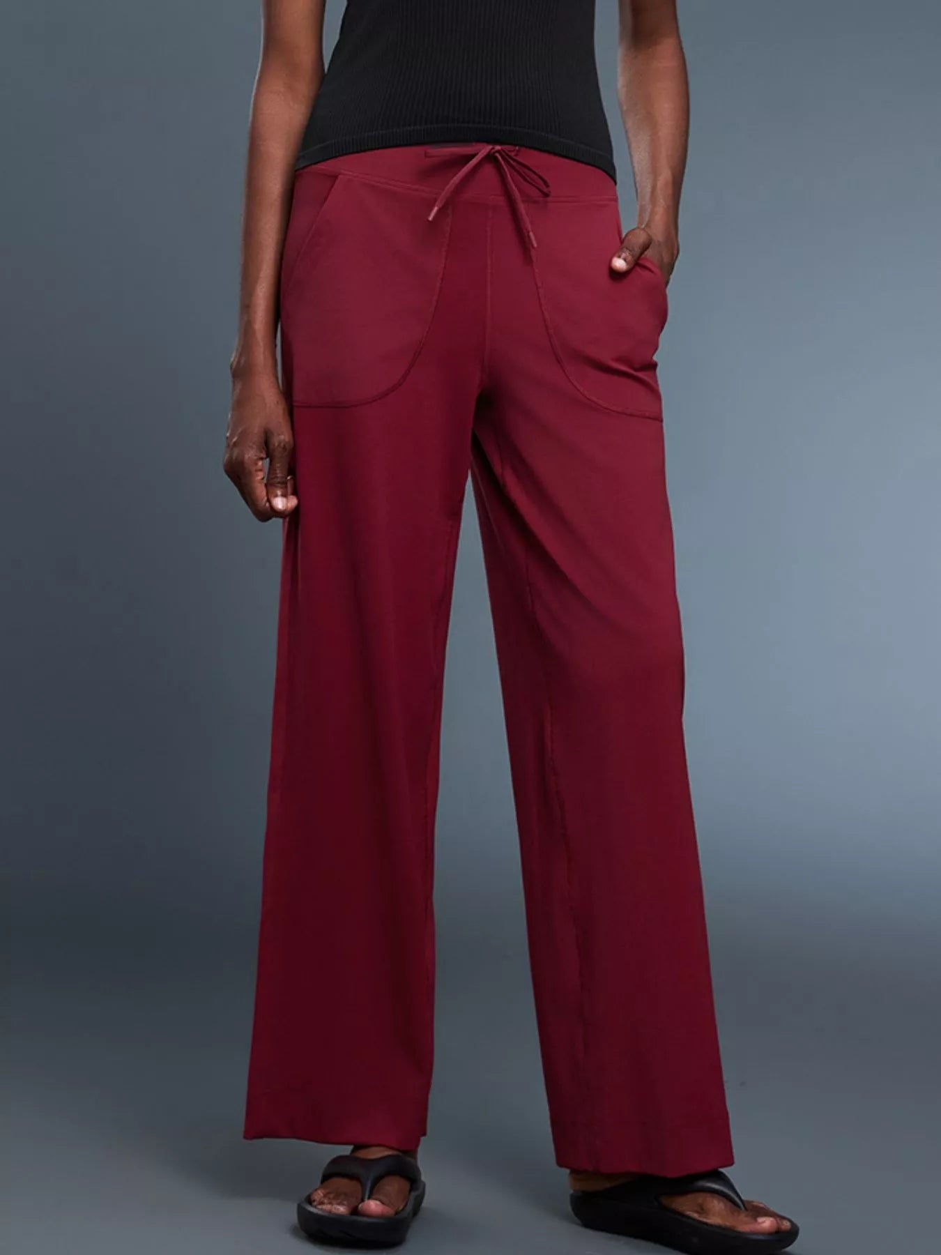 Person wearing maroon pants on a gray background