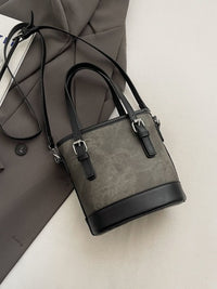 Gray handbag with black accents on a light gray surface