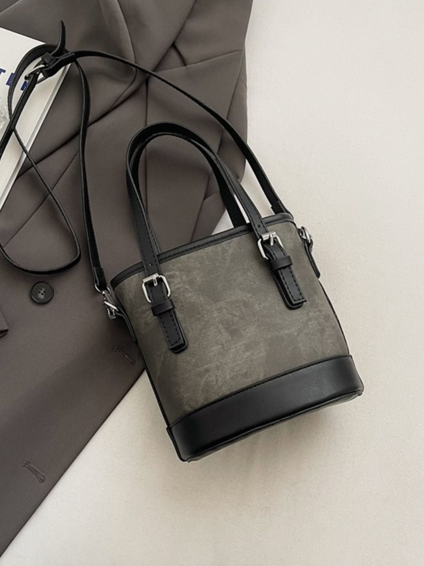 Gray handbag with black accents on a light gray surface