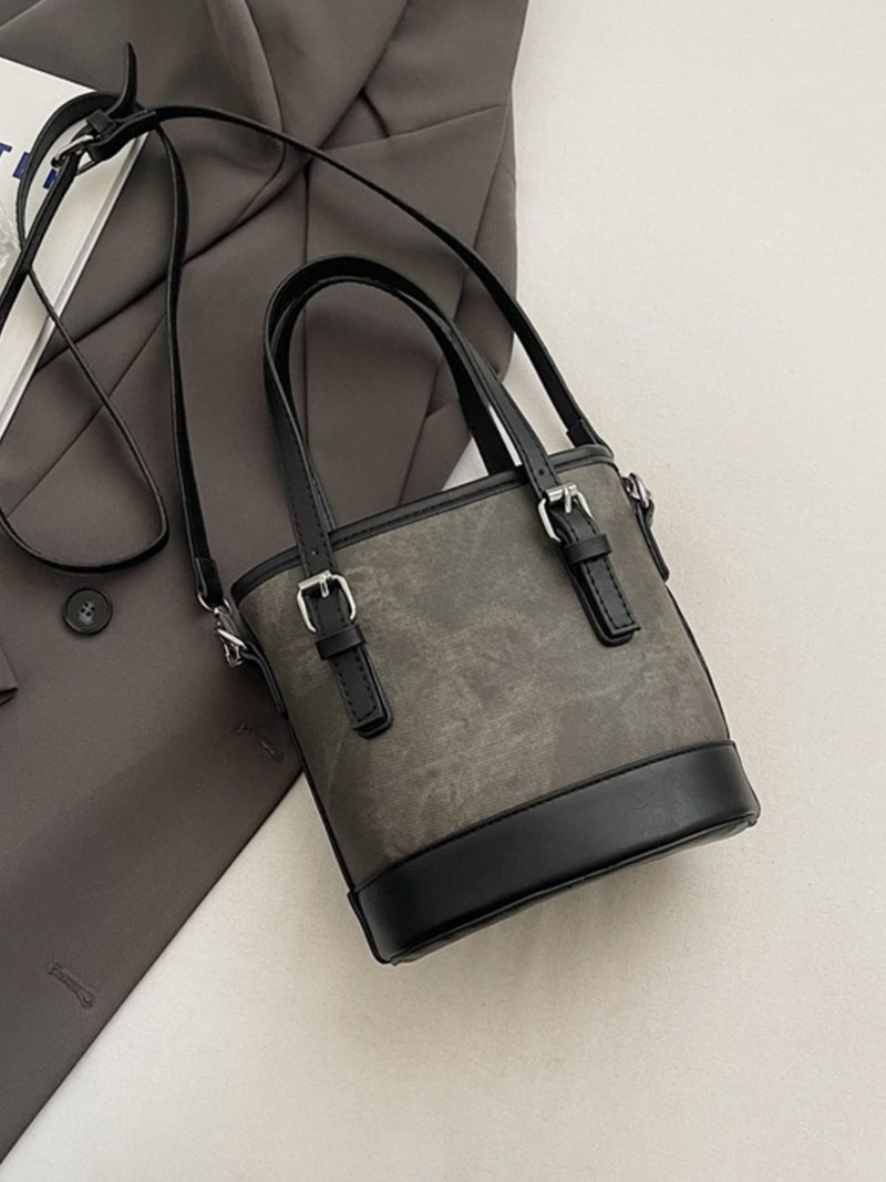 Gray handbag with black accents on a light gray surface